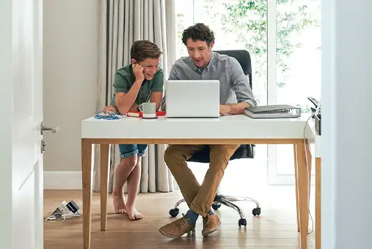 Father and son sitting at laptop desk