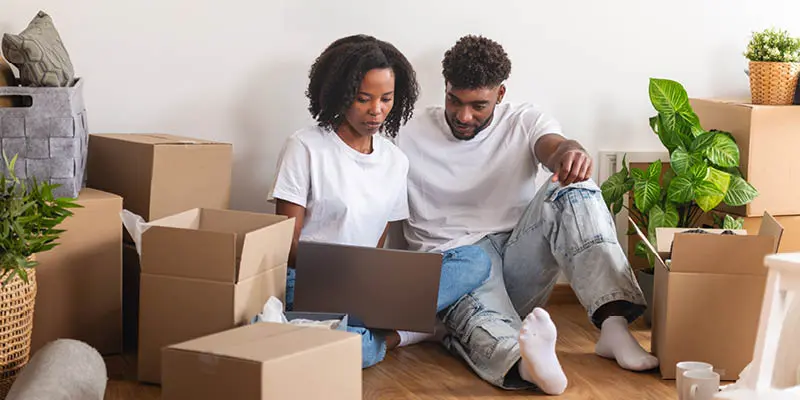 Couple using laptop on the floor while unpacking