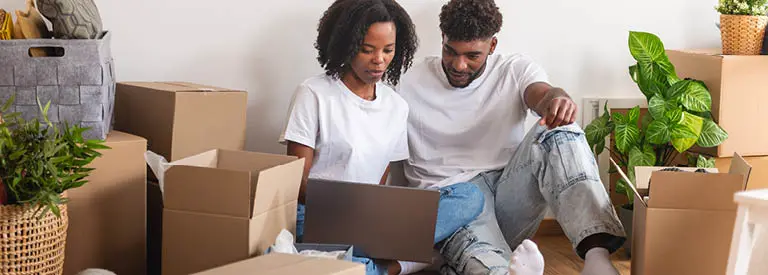 Couple using laptop on the floor while unpacking