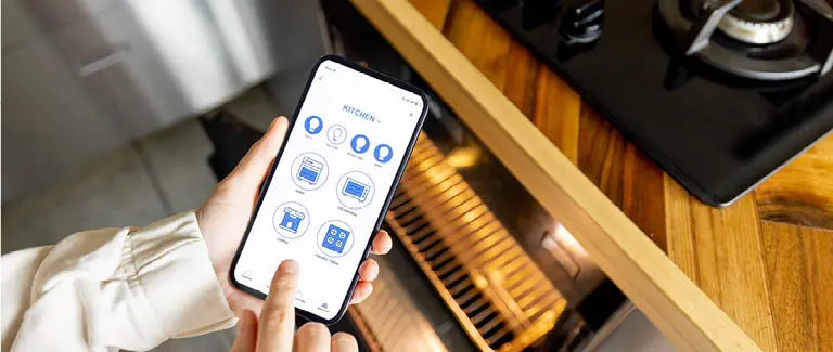 Hand holding smartphone controlling kitchen devices via app