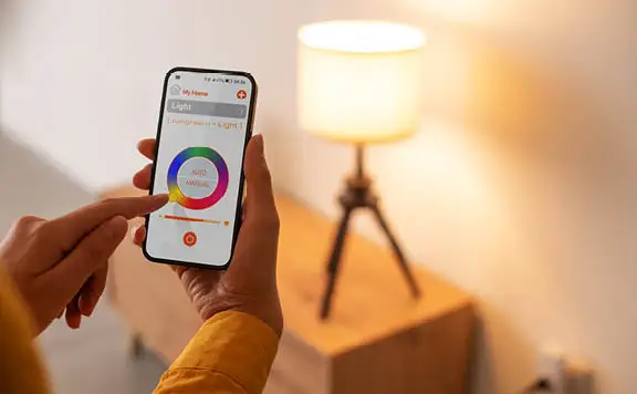 Lady adjusting light color from smart home app on phone