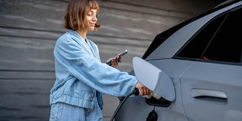 Woman plugging in her electric vehicle at home