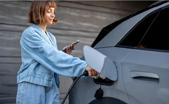 Woman plugging in her electric vehicle at home