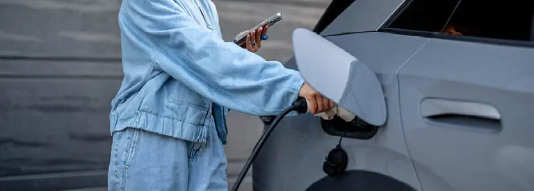 Woman plugging in her electric vehicle at home