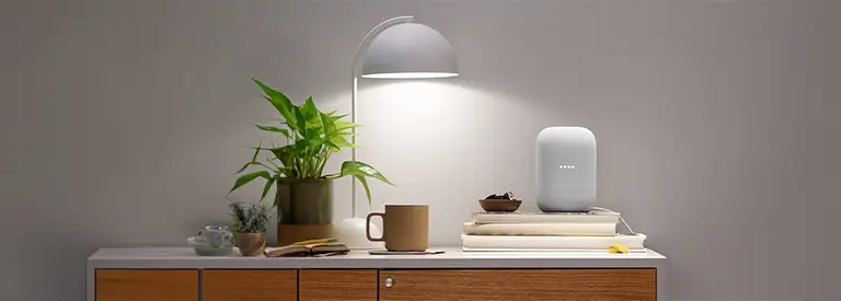 Google Home sitting on table with desk light