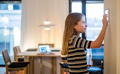 Little girl adjusting a thermostat on the wall
