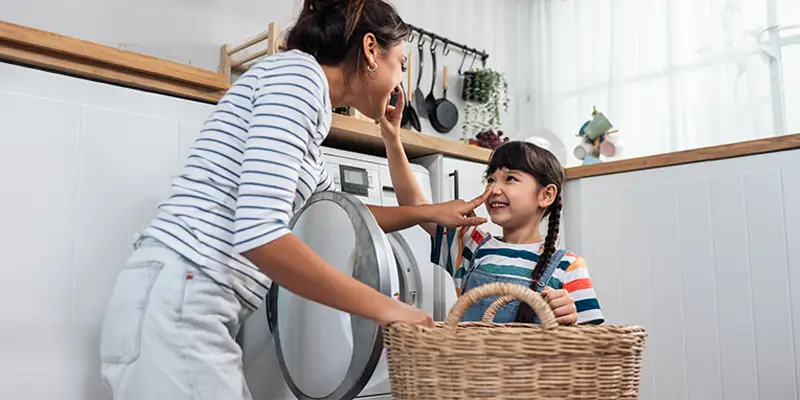 Mom and daughter having fun doing laundry