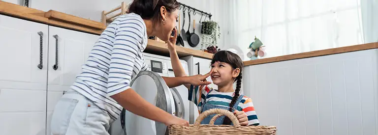 Mom and daughter having fun doing laundry
