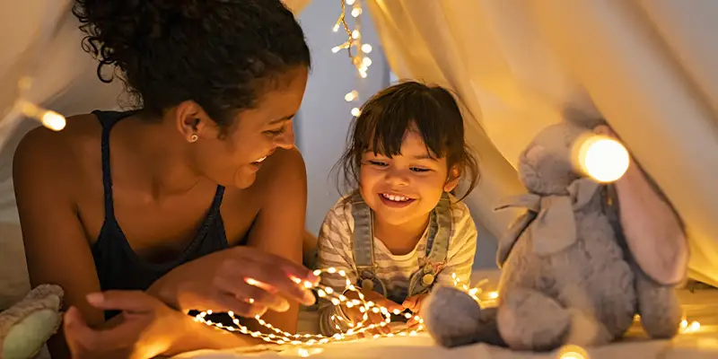 Mom and daughter in a fort with string lights