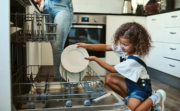 Mother daughter loading dishwasher