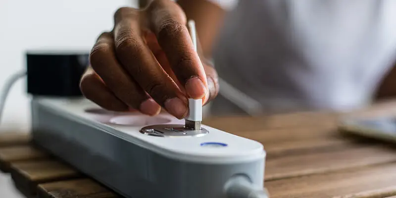 Hand plugging into smart power strip for energy