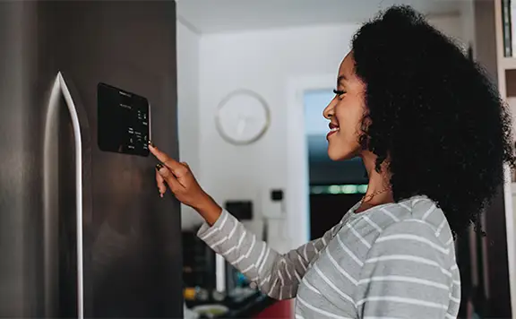 Woman using smart refrigerator at home