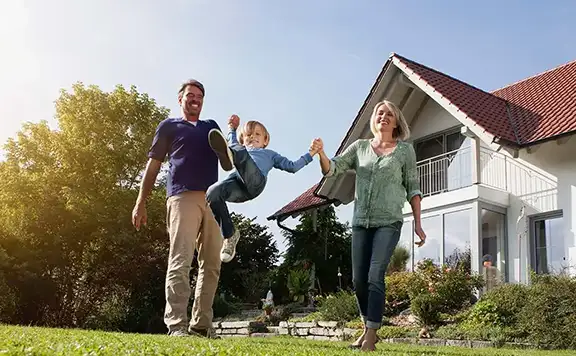 parents swinging their child in the front yard