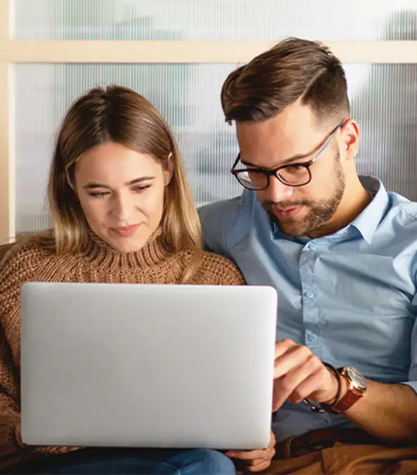 Couple sitting on a couch using laptop together