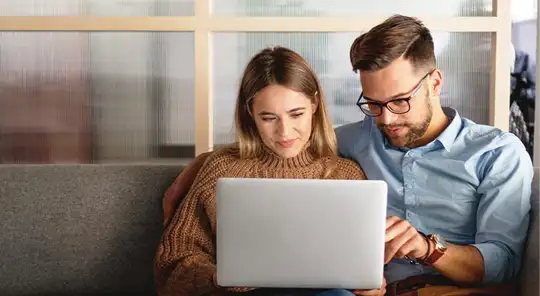 Couple sitting on a couch using laptop together