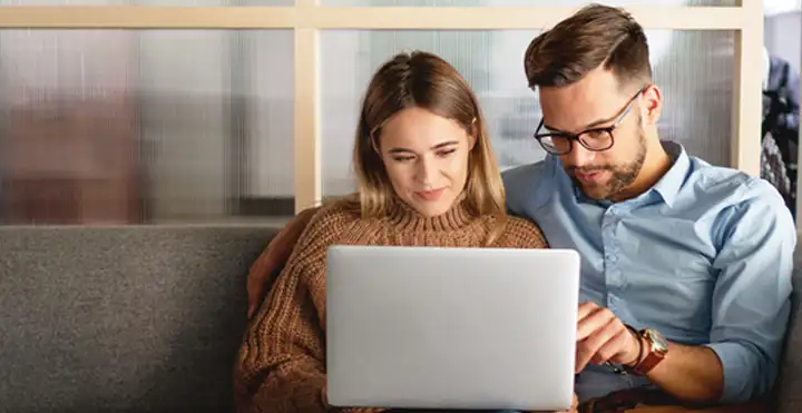 Couple sitting on a couch using laptop together