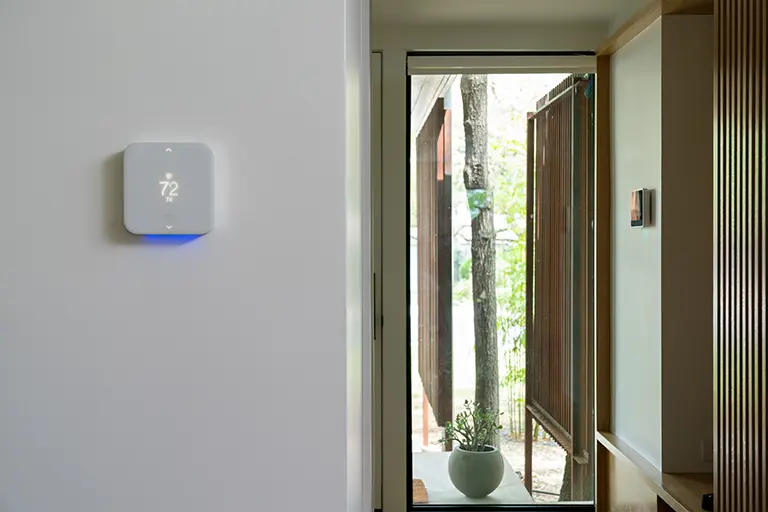 person relaxing while their thermostat automatically adjusts