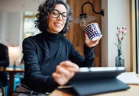 Woman enjoying coffee using a tablet. 