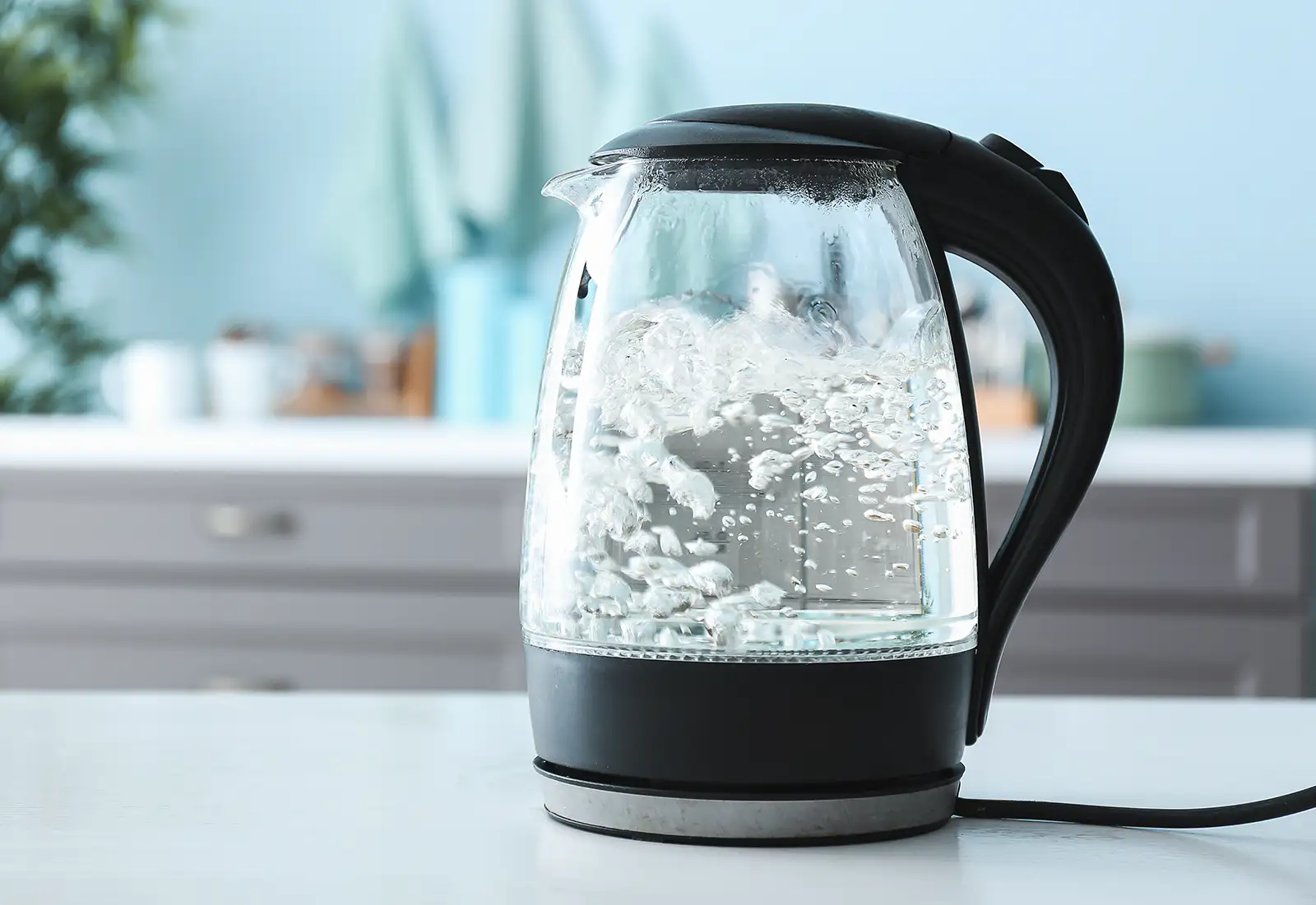 An electric kettle filled with boiling water, sitting on a countertop