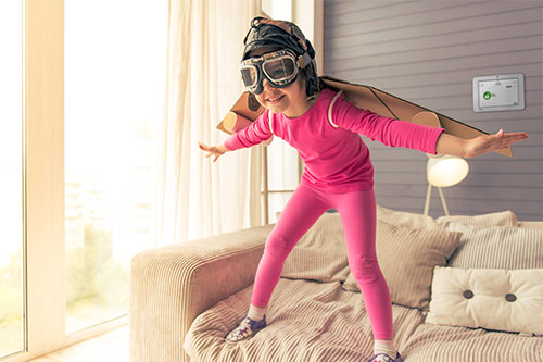 Child with cardboard wings and helmet with goggles pretending to fly. 